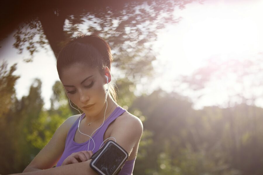 Young sportswoman listening to music in park