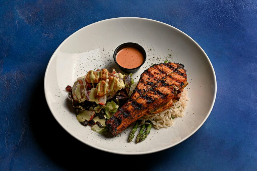 Plate of grilled salmon and rice on a blue background